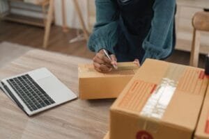 eBay seller, working from his home office, shipping packages and writing on label.
