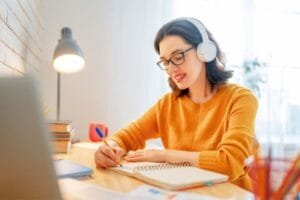 Woman working at home and writing in notebook at table.